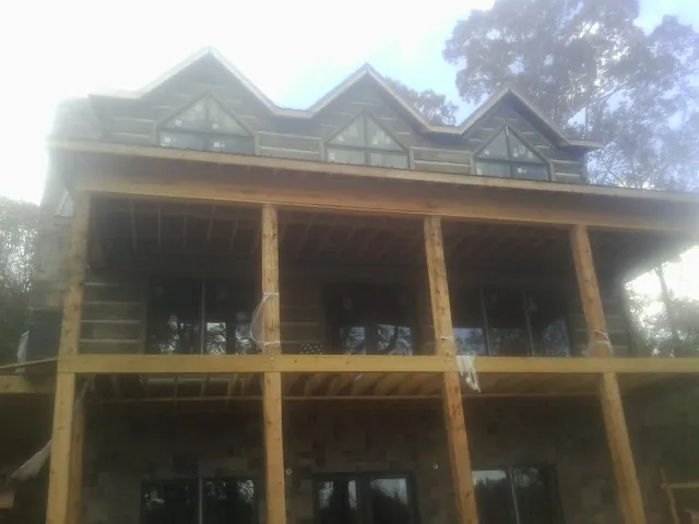 Dormers and porch framing on a large log home under construction — Roof Coating work by our crew in Hume