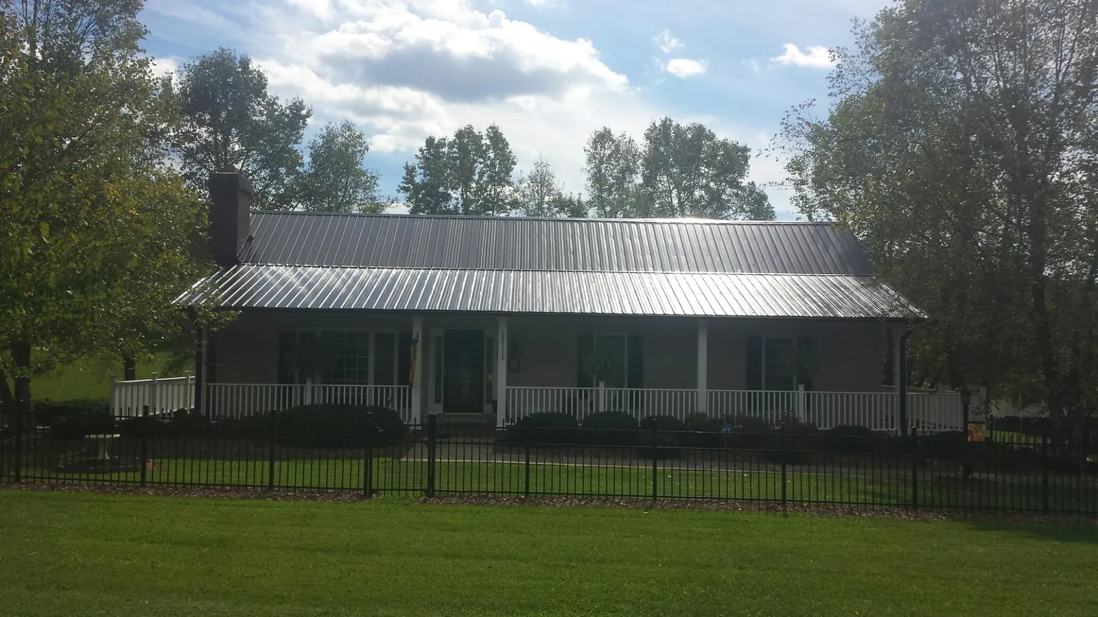 Gray metal roof on a brick ranch with a full width front porch — Gutter Guard Installation work by our crew in Hume
